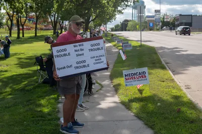 A man holds a sign reading "Good Trouble — We Will Not Be Silent" at the Good Trouble rally in Brookings, South Dakota.